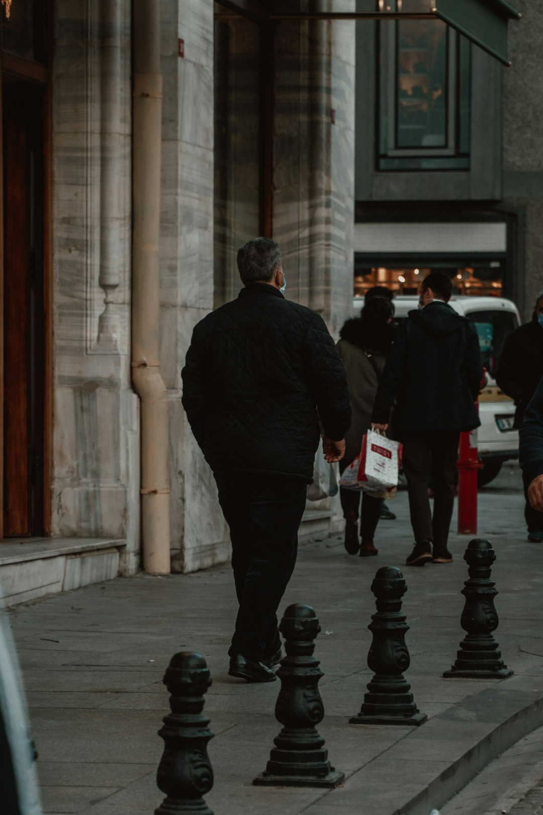 man in black jacket walking on sidewalk during daytime