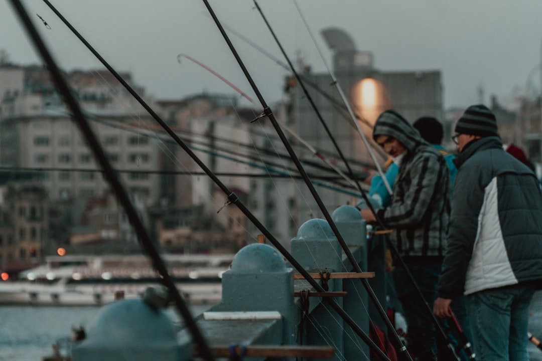 man in black jacket standing on blue metal fence during daytime