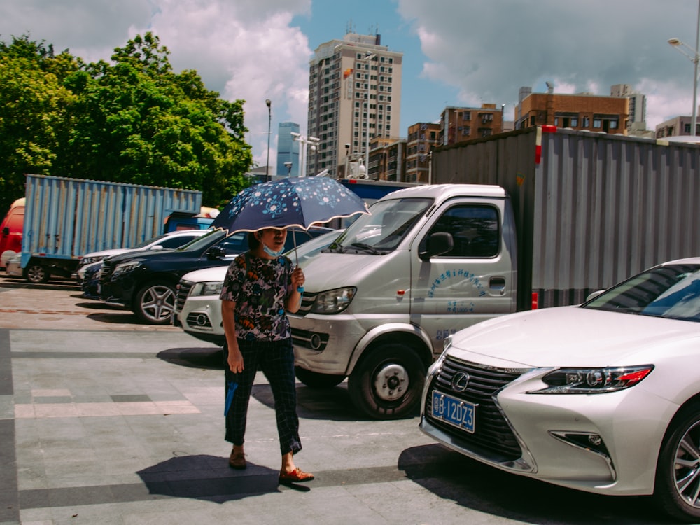 woman in black and white jacket holding umbrella standing beside white car during daytime