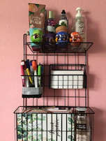 Slim, wall-mounted shelving holding neatly arranged makeup products and brushes in a bright bathroom.
