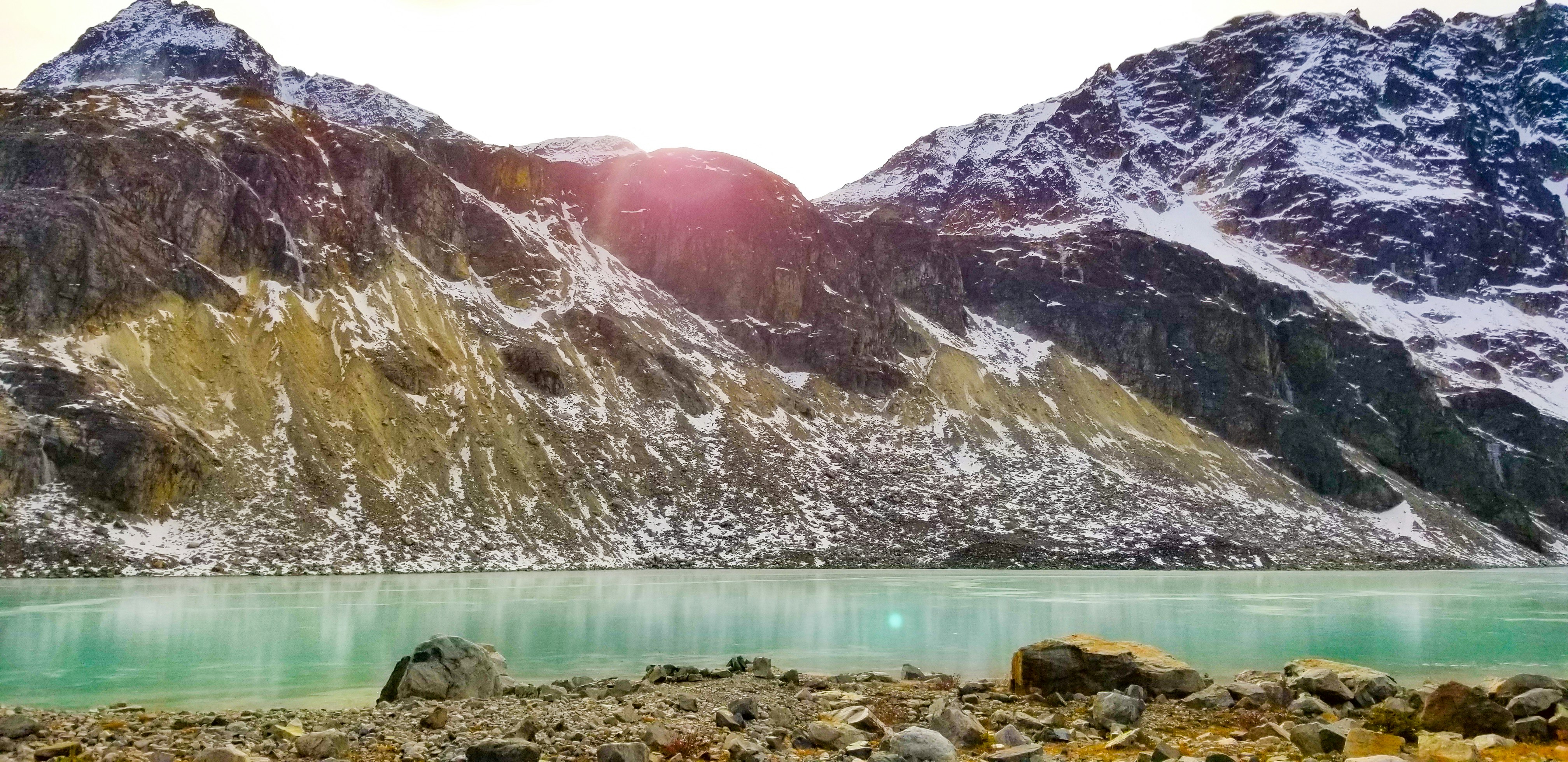 brown wooden dock on lake near snow covered mountain during daytime