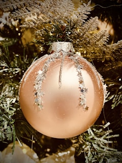 A close-up of a shimmering gold foil Christmas card featuring a delicate hand-drawn wreath.