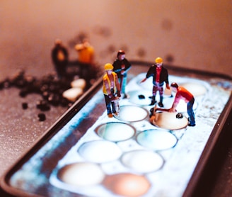 tiny model construction workers, working on a mobile phone screen 