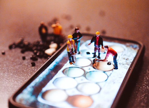 tiny model construction workers, working on a mobile phone screen 