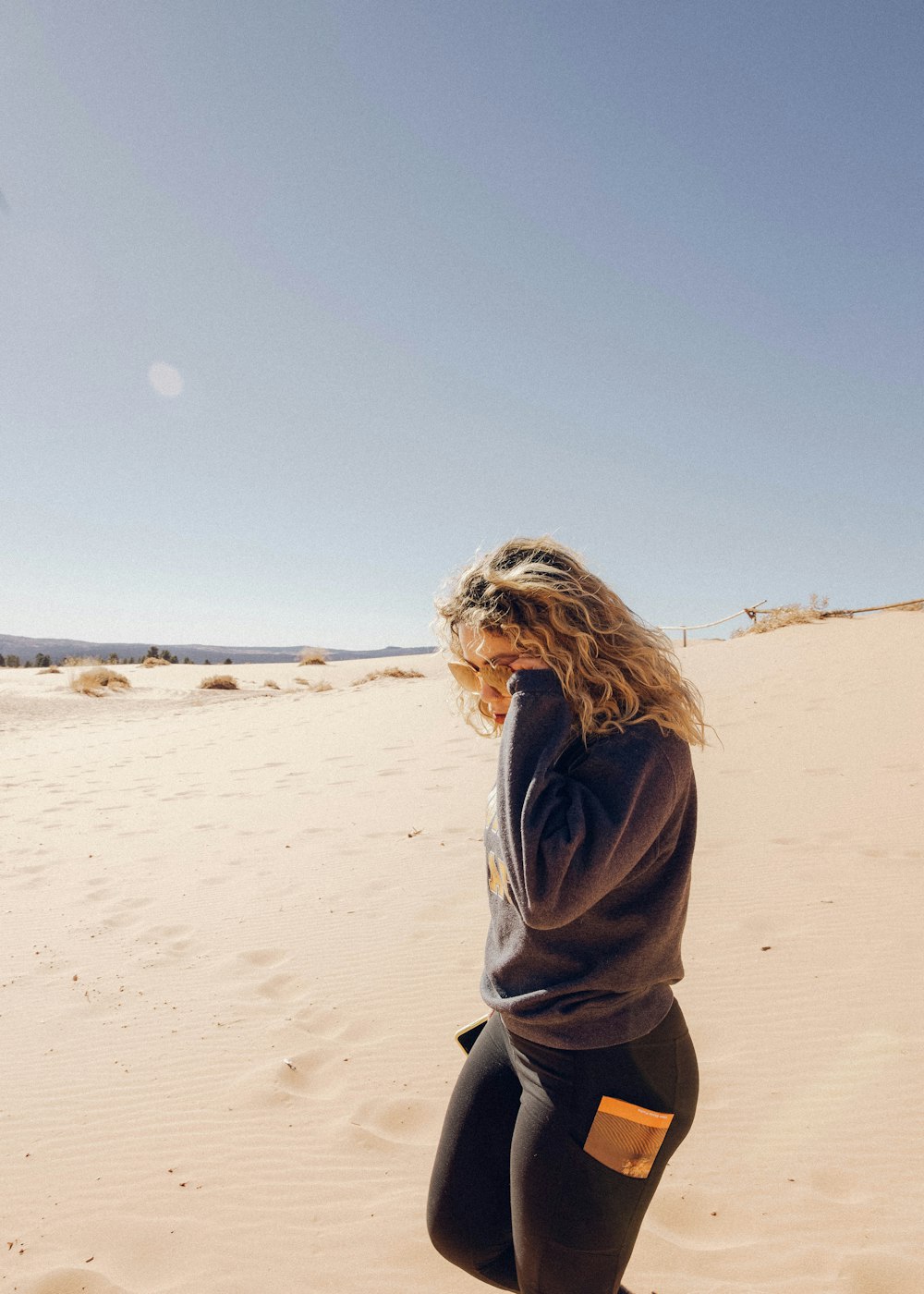 woman in gray hoodie standing on brown sand during daytime