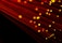 Numerous strands of glowing red-orange fiber optic cables create a dynamic and futuristic visual. The bright points of light accentuate the flowing lines against a dark background, giving a sense of motion.