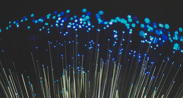 Clusters of blue lights on the tips of fiber optic cables create a captivating visual of glowing dots against a dark background.