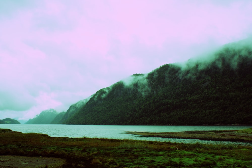 body of water near mountain during daytime