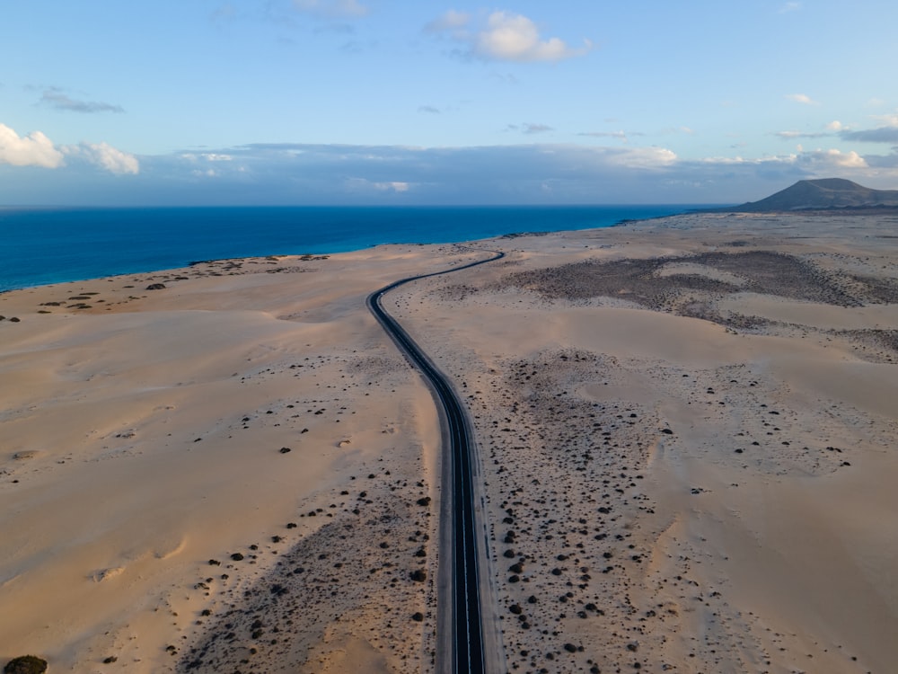 arena marrón cerca del cuerpo de agua durante el día