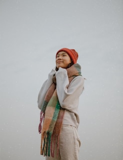 A peaceful moment by a Finnish cabin, showing a person wrapped in a finvaa scarf, gazing at the northern sky.