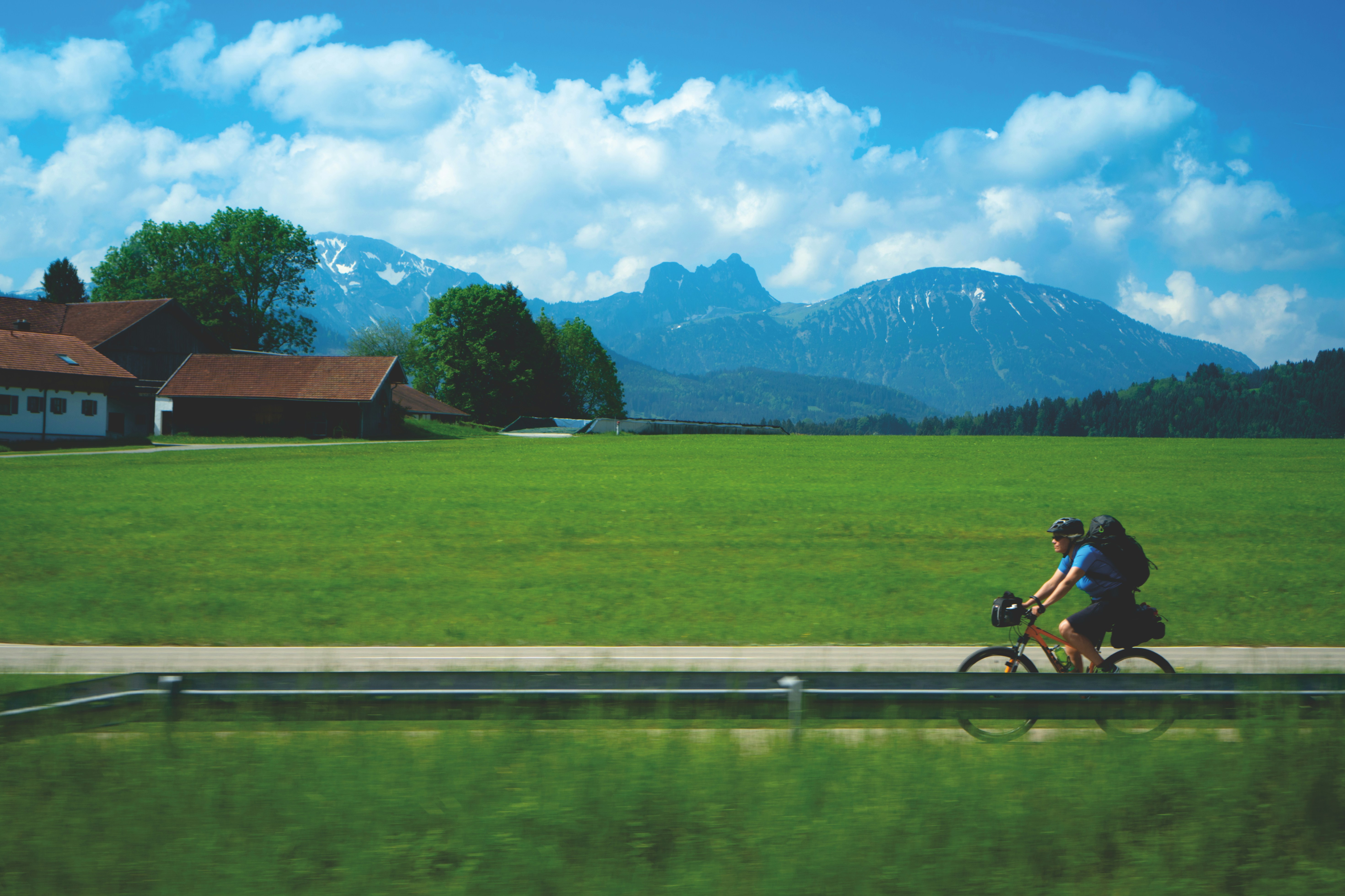 man riding bicycle on road near green grass field during daytime