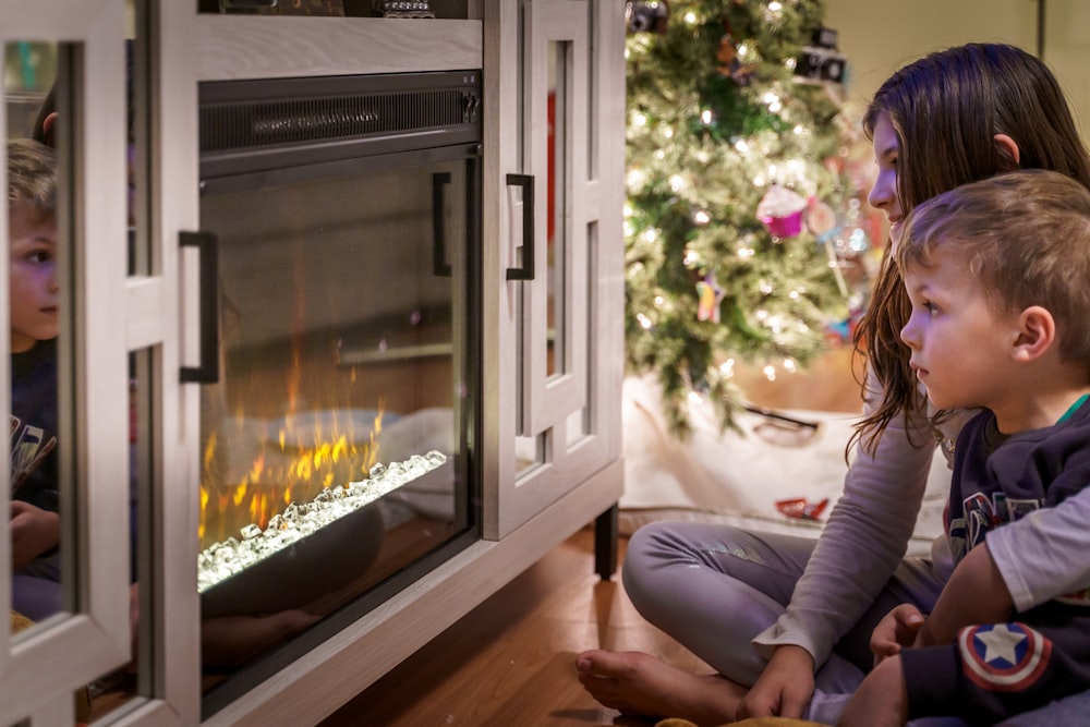 woman in gray long sleeve shirt sitting on floor beside fireplace