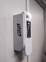 Germac chemical dispensers mounted on a clean white wall in a hospitality laundry setting.