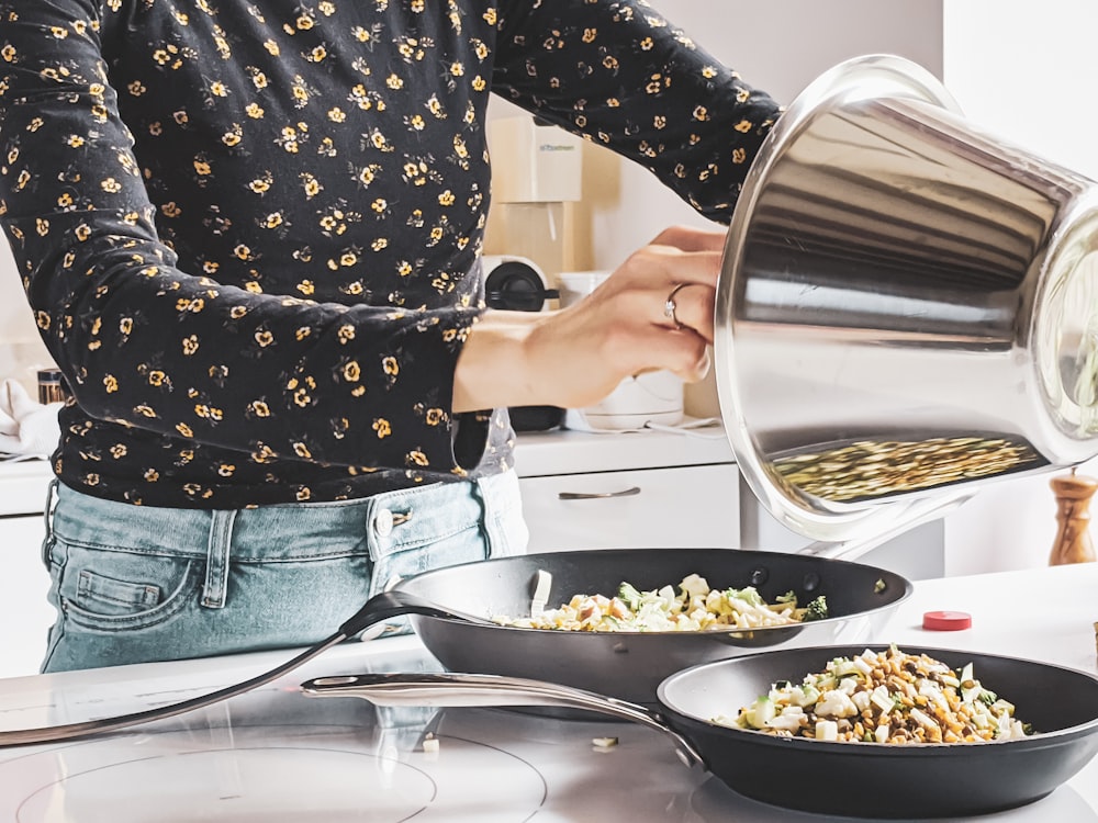 woman in black and white polka dot shirt and blue denim jeans holding stainless steel cooking