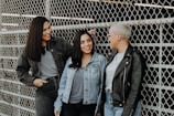 3 women standing beside gray metal fence