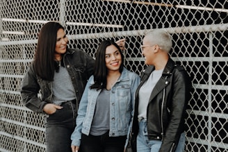 3 women standing beside gray metal fence