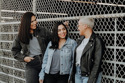 3 women standing beside gray metal fence
