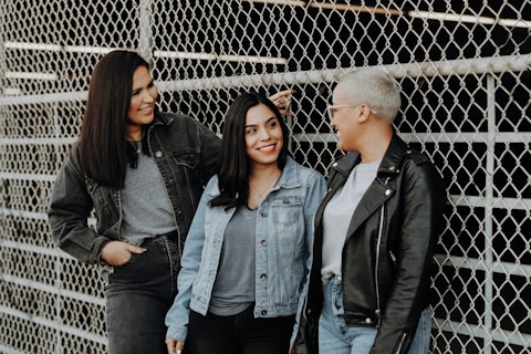 3 women standing beside gray metal fence