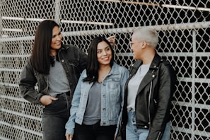 3 women standing beside gray metal fence