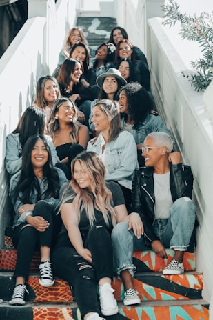 A group of friends laughing and wearing Lumina Apparel pieces while sitting on urban steps.