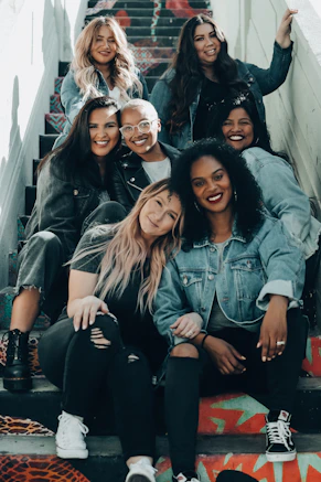 A group of seven women sitting together on colorful painted outdoor stairs