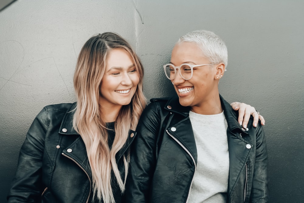 woman in black leather jacket beside woman in gray shirt