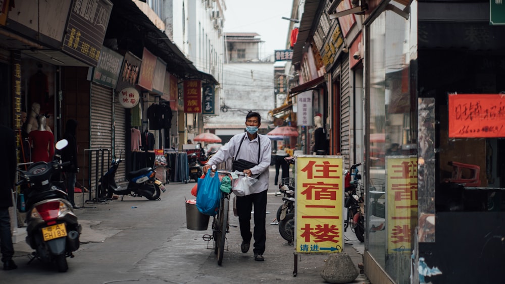 man in white shirt riding bicycle on street during daytime