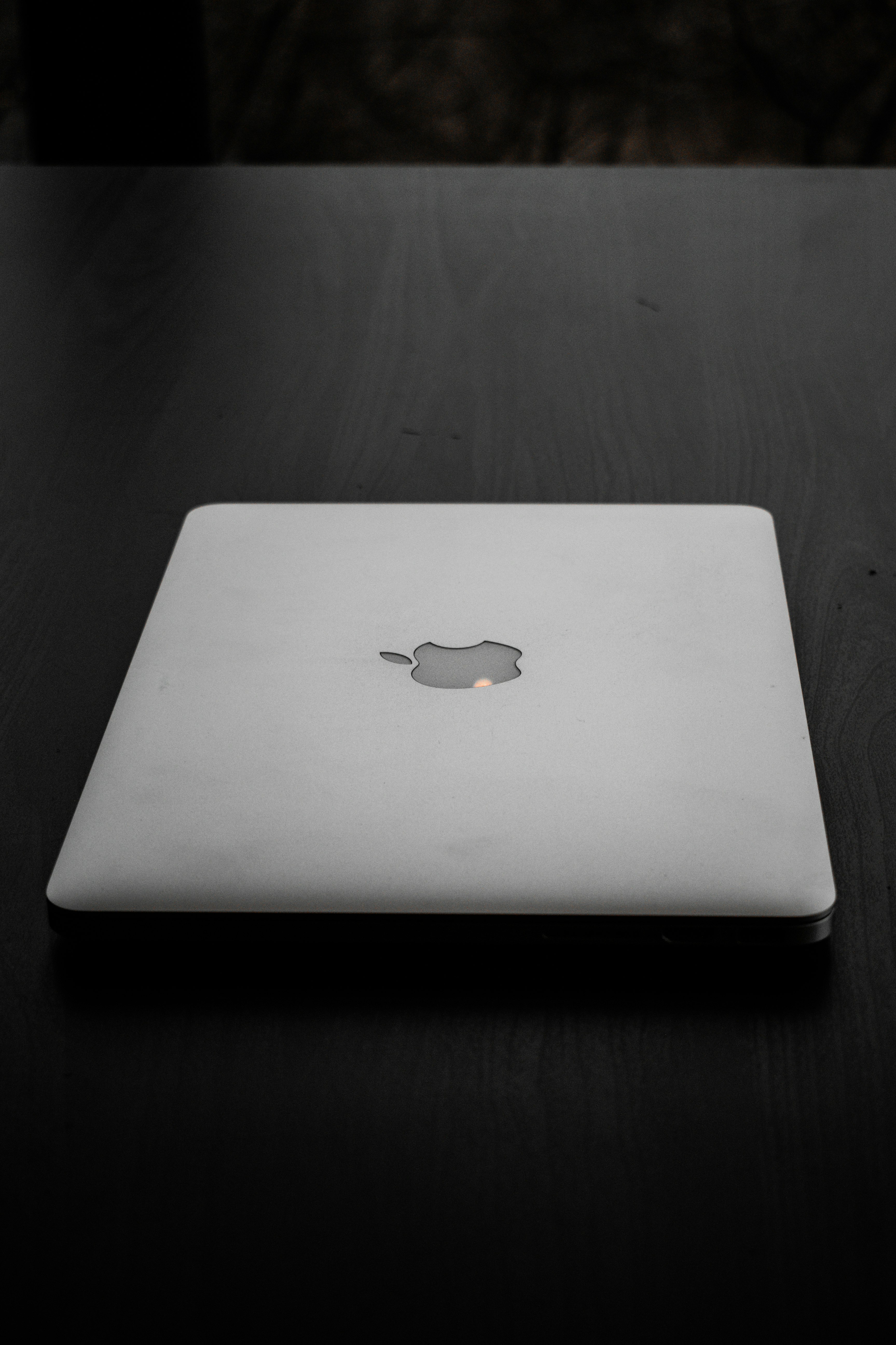 silver macbook on black table