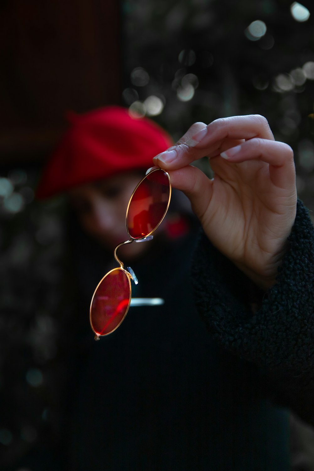 person holding red framed sunglasses