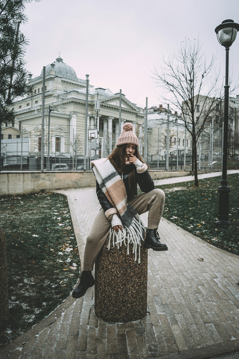 Donna in camicia a maniche lunghe a righe bianche e nere che si siede sulla panchina di cemento marrone