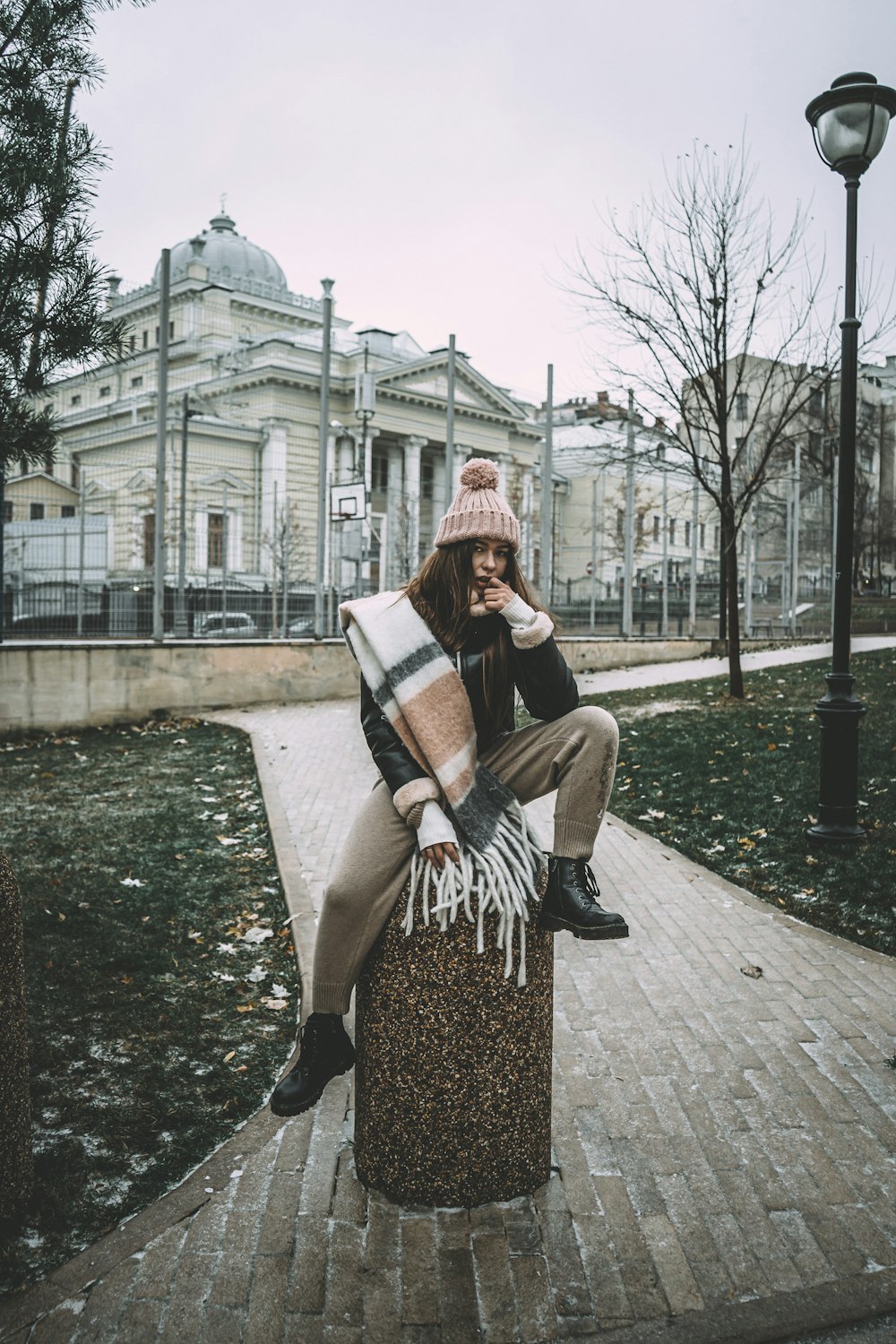 woman in black and white striped long sleeve shirt sitting on brown concrete bench