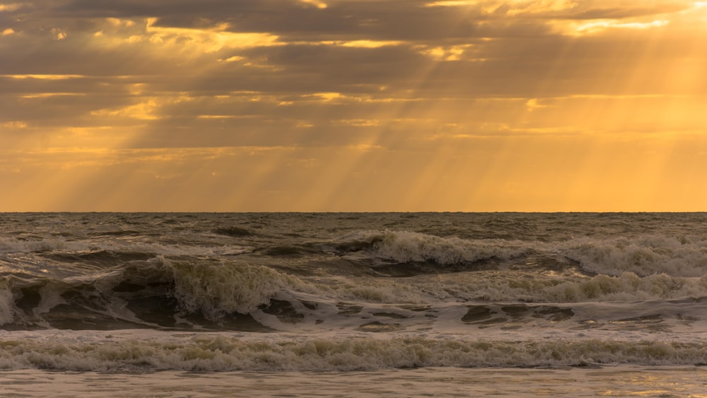 ocean waves crashing on shore during sunset