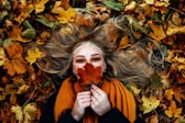 woman in black long sleeve shirt lying on brown leaves
