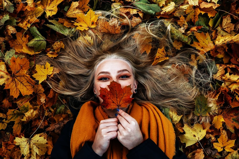 woman in black long sleeve shirt lying on brown leaves