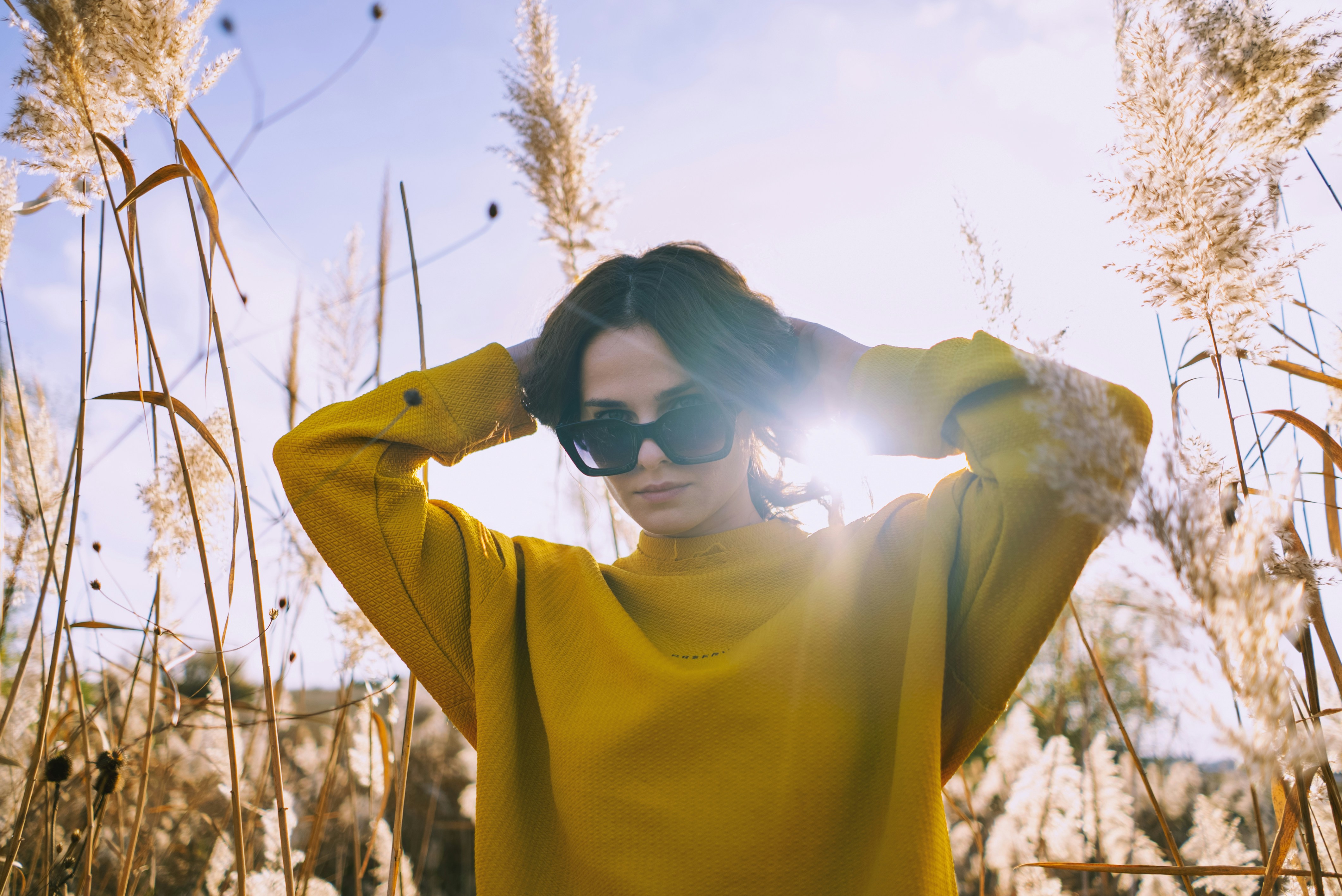 woman in yellow sweater wearing black sunglasses