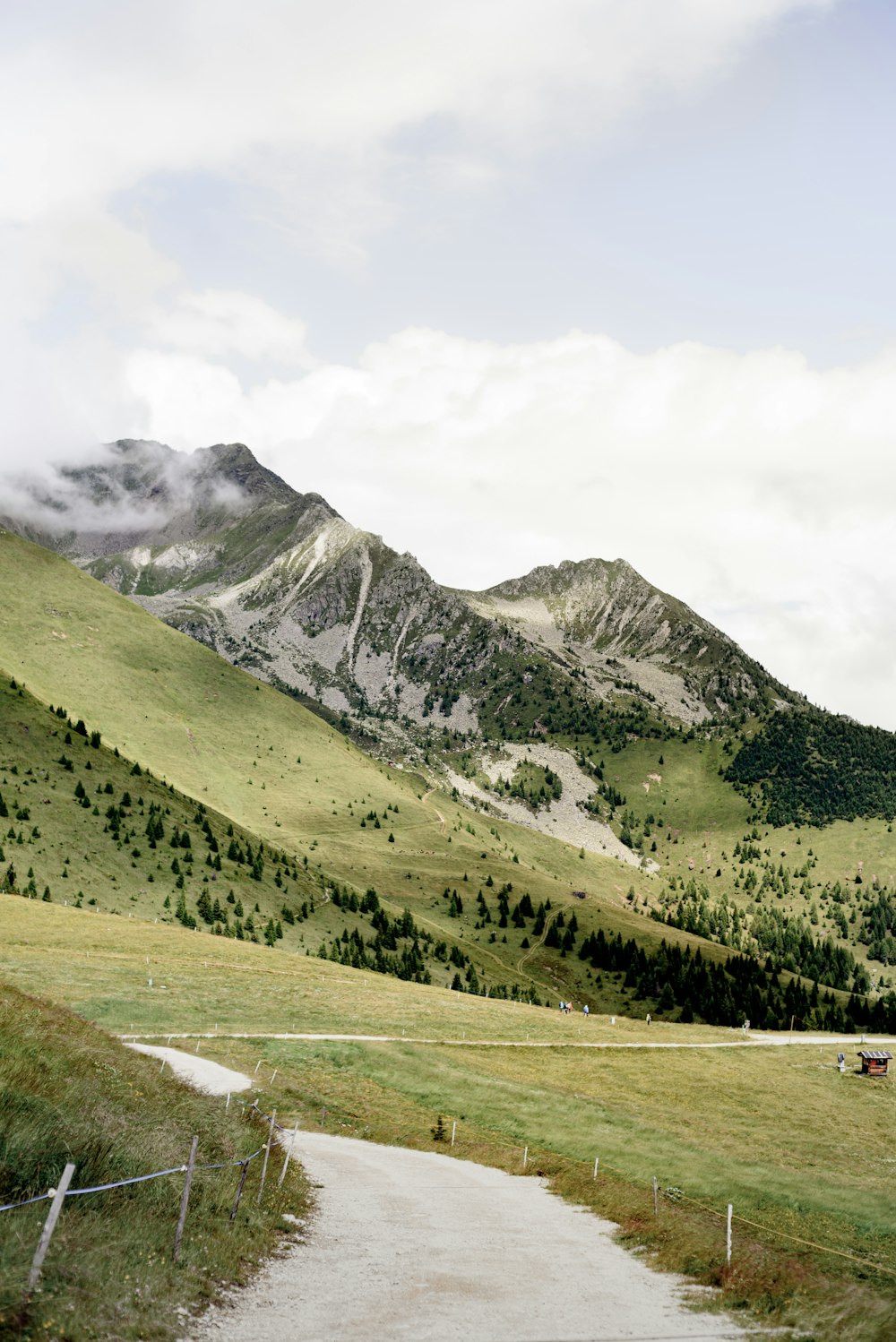 green grass field near mountain under white sky during daytime