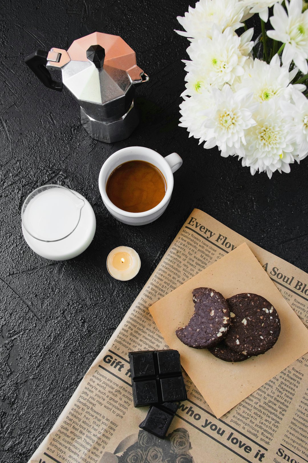 white ceramic teacup beside chocolate cookies on black table