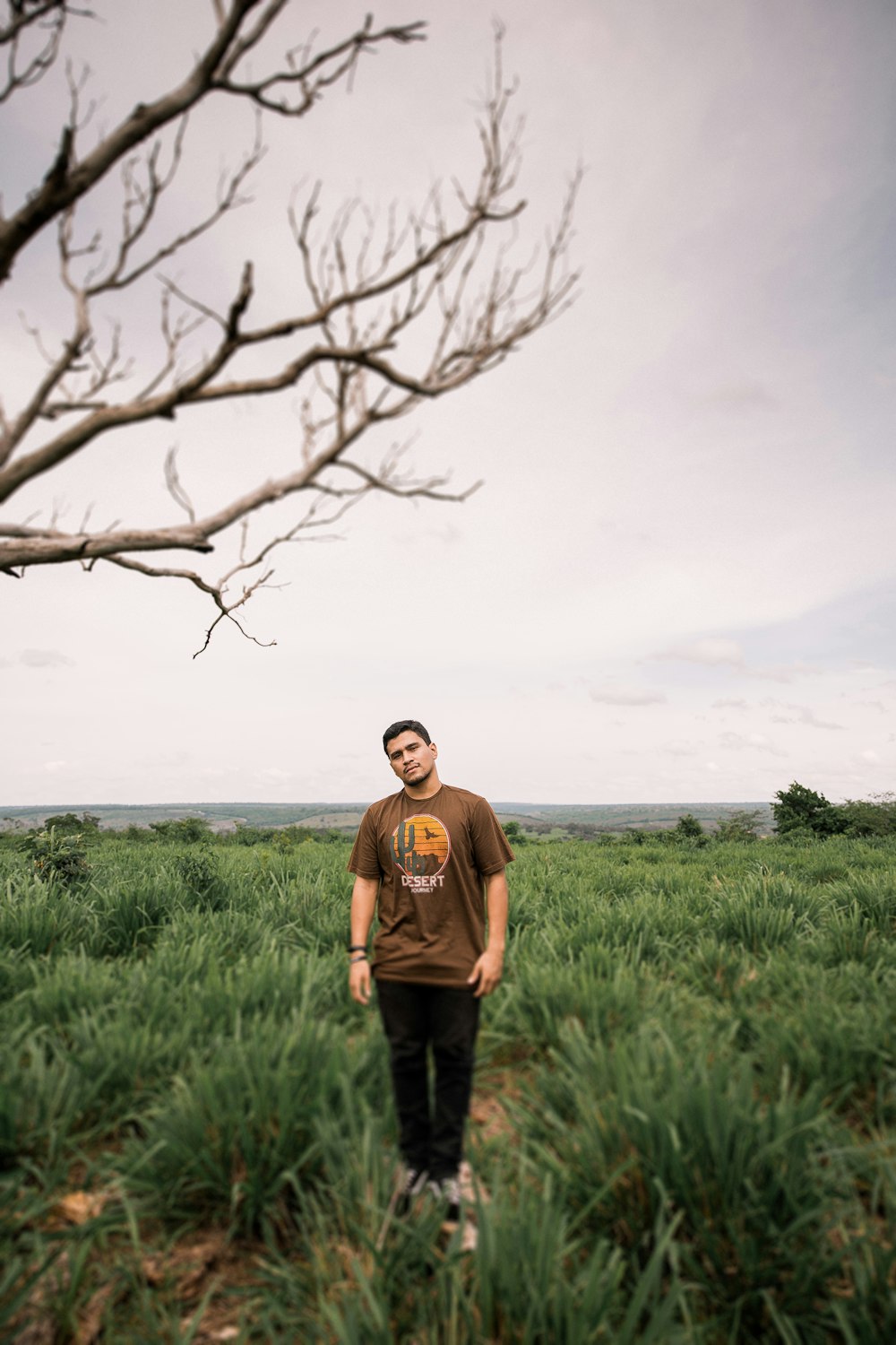 man in brown sweater standing on green grass field during daytime