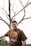 man in brown crew neck t-shirt standing beside bare tree during daytime
