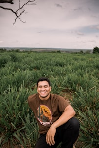 man in brown crew neck t-shirt sitting on green grass field during daytime