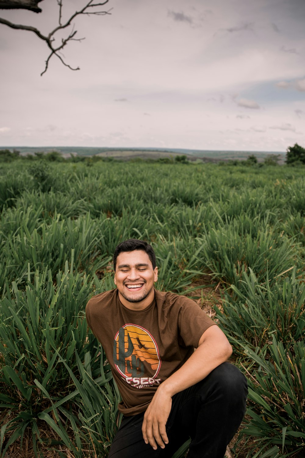 man in brown crew neck t-shirt sitting on green grass field during daytime