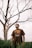man in gray crew neck t-shirt standing beside bare tree during daytime