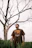 man in gray crew neck t-shirt standing beside bare tree during daytime