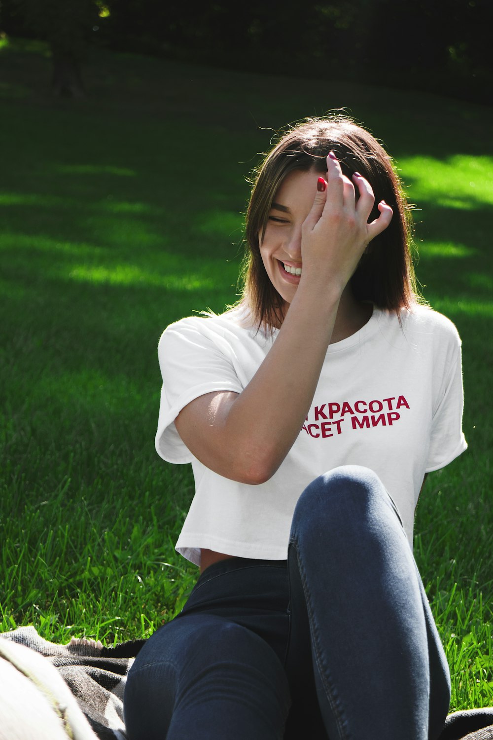 woman in white crew neck t-shirt and black pants sitting on green grass field