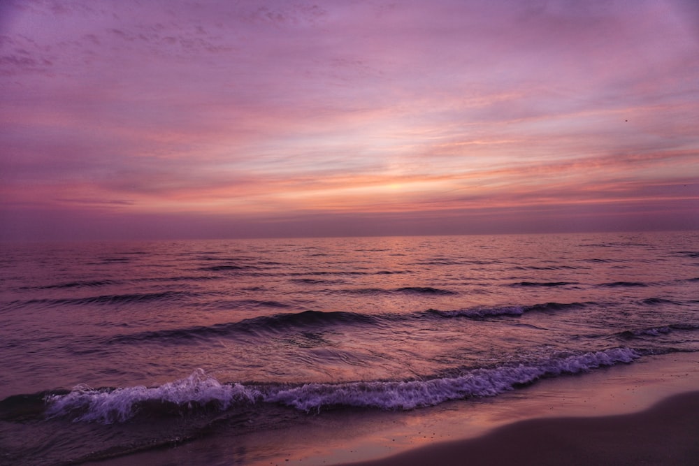 ocean waves crashing on shore during sunset