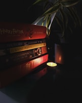 A stack of inspirational books with elegant typography, accented by a gold pen and soft candlelight.