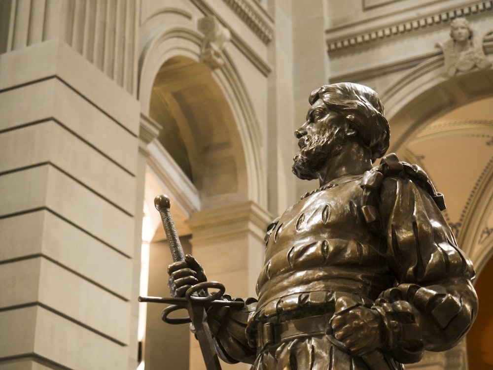 estatua de oro del hombre sosteniendo la espada