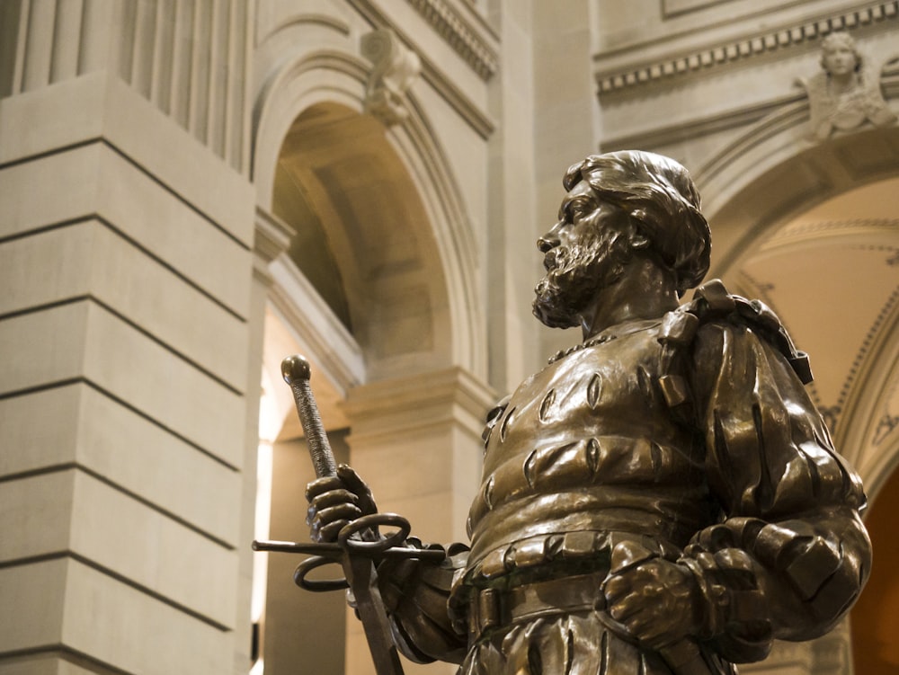 gold statue of man holding sword