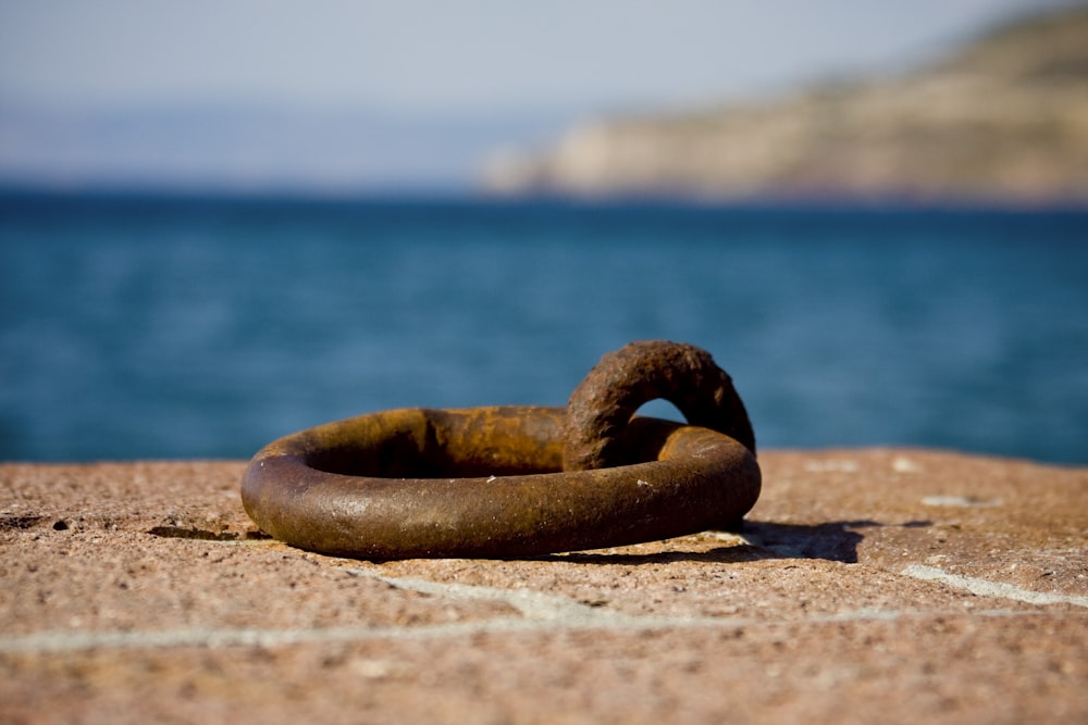 brown steel ring on brown sand near body of water during daytime