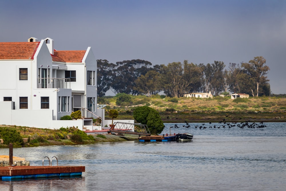 Casa de concreto branco e vermelho ao lado do corpo de água durante o dia
